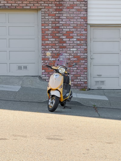 黄色和黑色摩托车停在棕色砖墙旁边